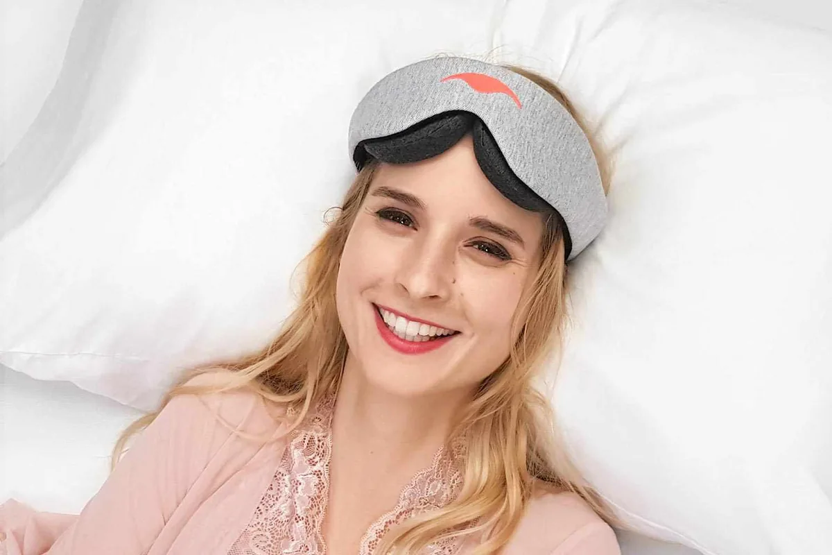 Woman lying in bed wearing the Manta Original sleep mask
